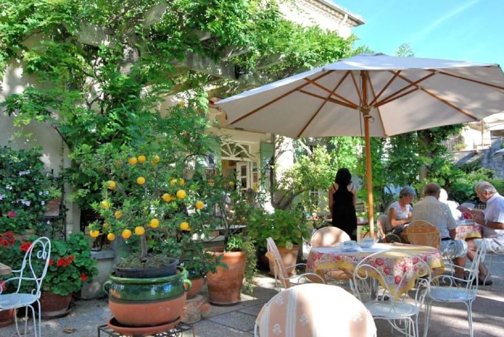 Een culinair restaurant met tafels en stoelen onder een parasol.